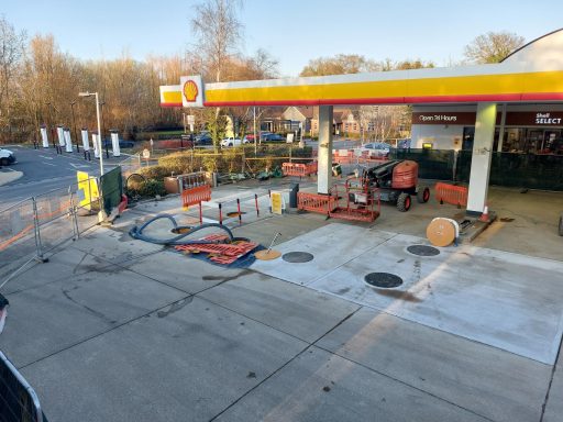 A partially closed Shell petrol station with construction barriers and equipment visible.
