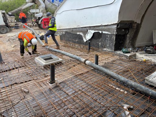 Construction workers are installing rebar and pipes on a building site.