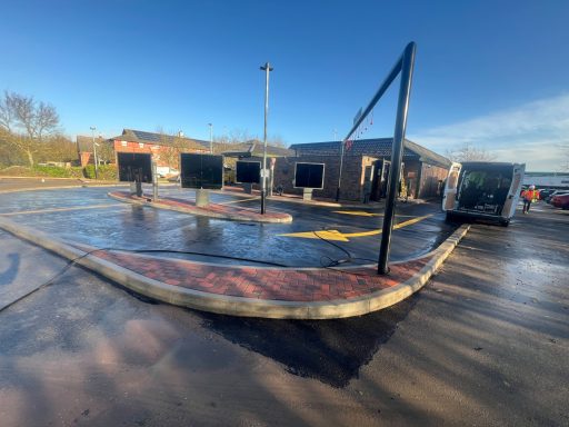 Drive-thru area with multiple order screens and a coffee shop in the background.